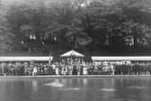 The official opening ceremony for Roundhay Park open air swimming pool in June 1907.. Guests dressed in the fashion of the period are seated on standing round the pool, with more behind on the embankment. A lone swimmer is testing the water.