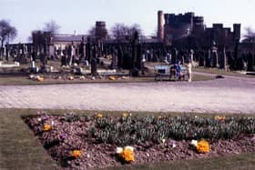 New Wortley Cemetery looking across Hall Lane to Armley jail. A woman and child are by a bench in the cemetery.