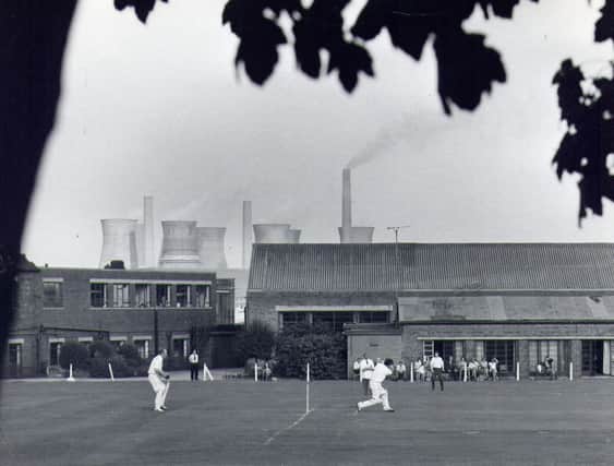 A game of cricket taking place on the sports field for staff at John Waddington's printing factory, off Wakefield Road, Thwaite Gate. The cooling towers of Skelton Grange Power Station can be seen above the rooftops. Waddingtons printing factory was founded in the 1890s and was well known for producing playing cards, theatre bills and board games, especially Monopoly. The factory was demolished around 1992.