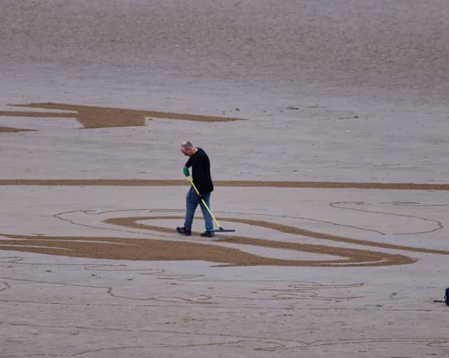 Artist, Fred Brown, working on a sand sketch of the Three Lions logo at Bridlington, while England beat Slovakia in the Euros.