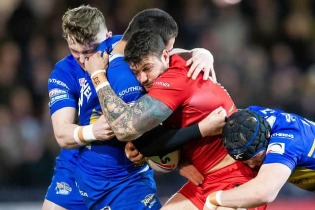 Jay Pitts is tackled by Leeds' Tui Lolohea and Matt Parcell.